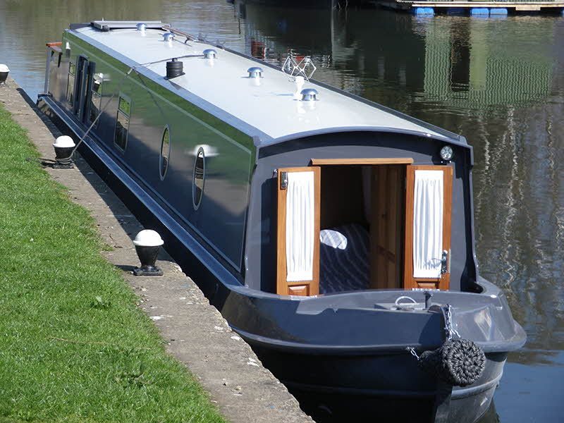 Grey narrowboat moored at canal side with Ajax marine security